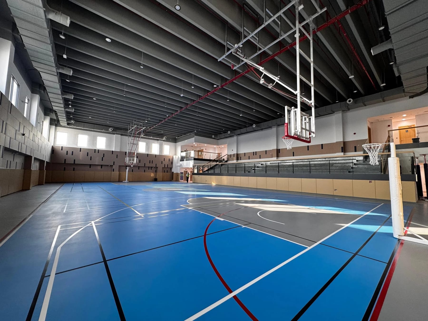 An empty indoor sports hall with a blue floor.